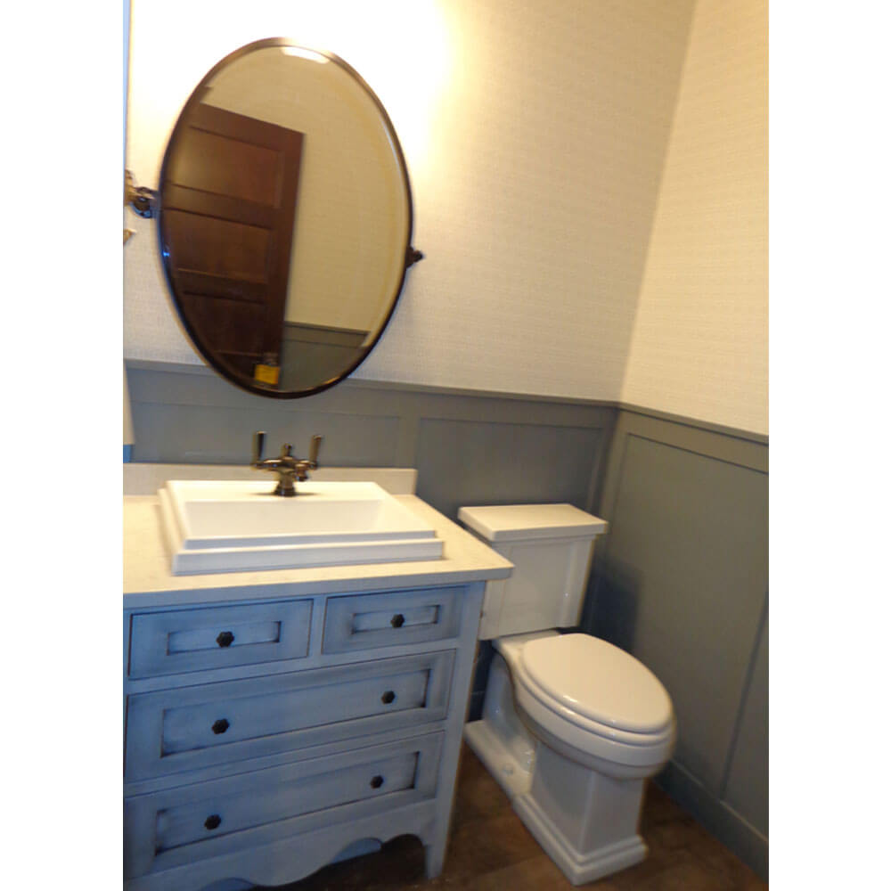 An oval mirror over a rustic white bathroom sink