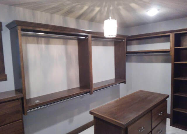 A grey room with a light suspended from the ceiling and shelves