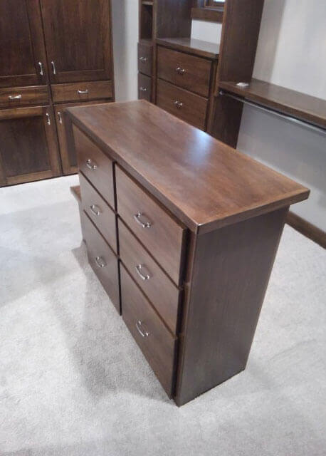 A compact dark wood shelving unit with drawers