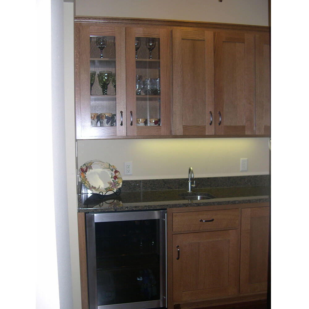 A small silver fridge in a kitchen with a dark grey countertop