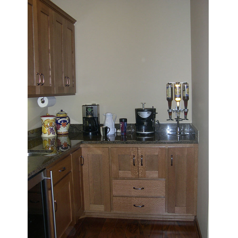 A bar area in a kitchen with wood cabinets and a dark counter