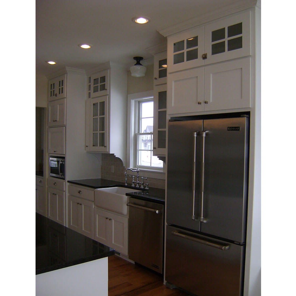 White kitchen cabinets and a larger silver fridge