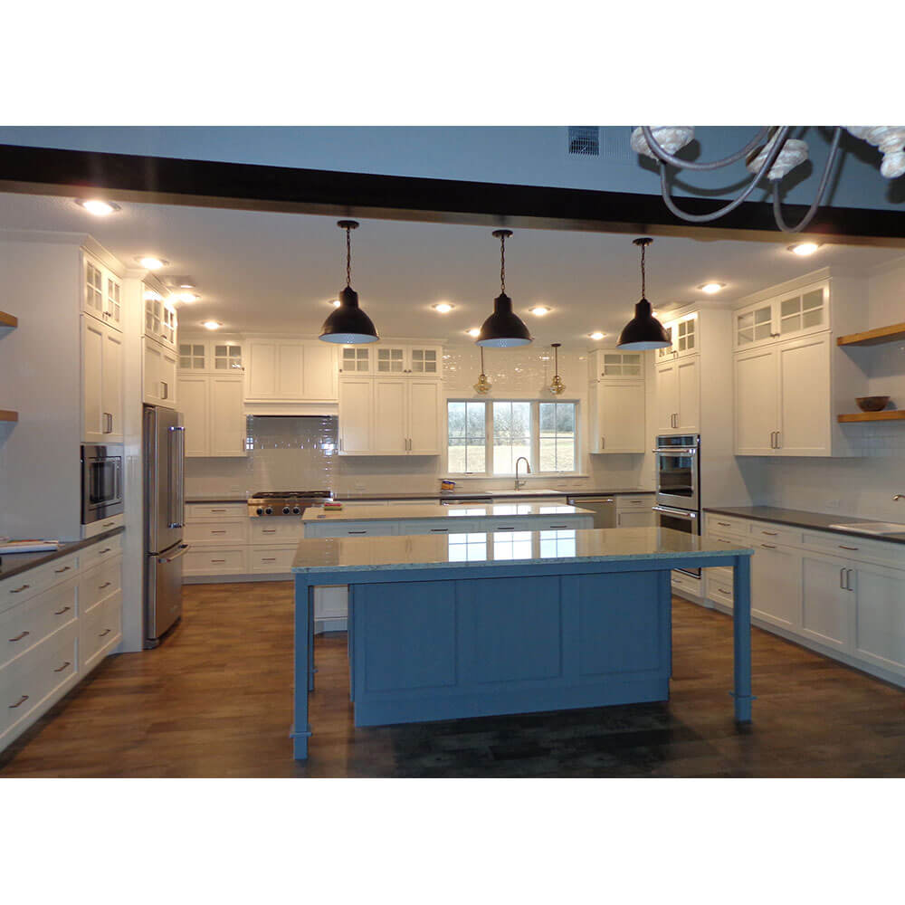 A large white kitchen with a blue island and a hardwood floor