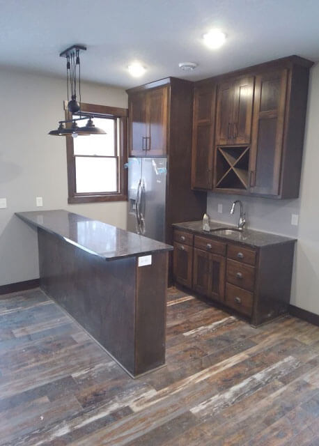 A kitchen with dark wood cabinets and rustic flooring
