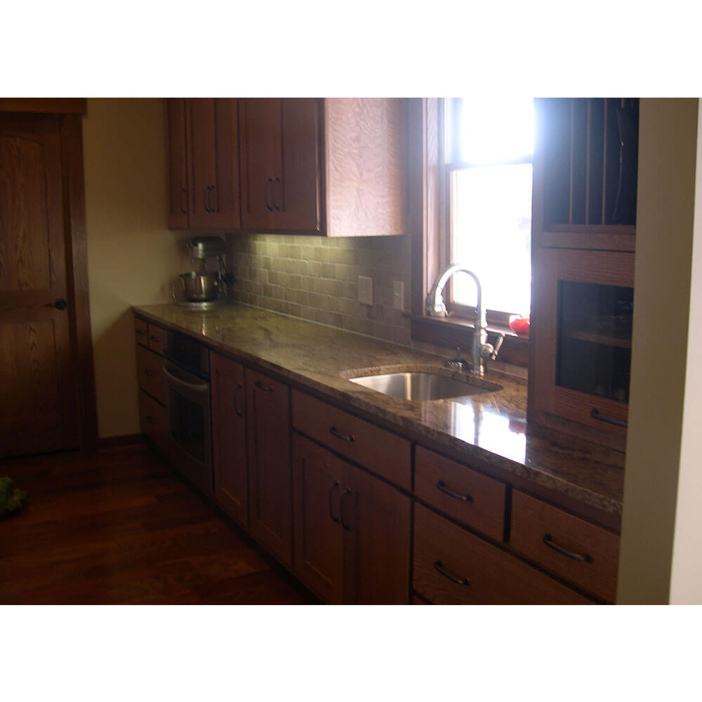 A landscape photo of wood kitchen cabinets with a granite countertop