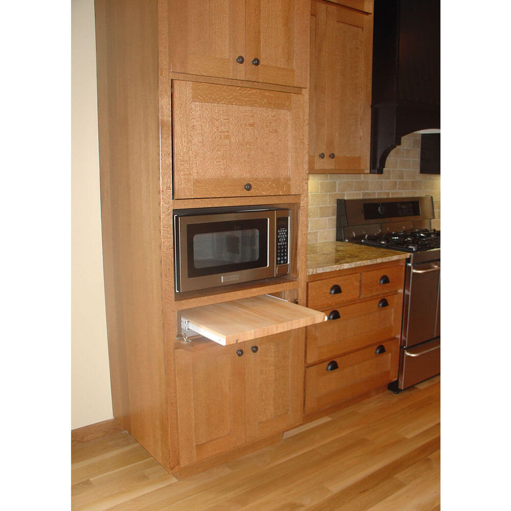 A pullout cutting board under a microwave oven